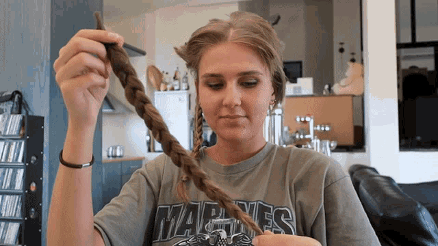 a woman wearing a marines shirt holds a braided ponytail
