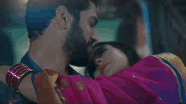 a man is kissing a woman on the forehead in a dark room .