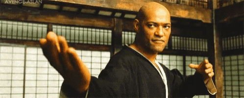 a bald man is standing in a room with his arms outstretched and pointing .