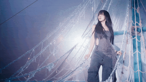 a woman with long black hair is standing in a room with ropes