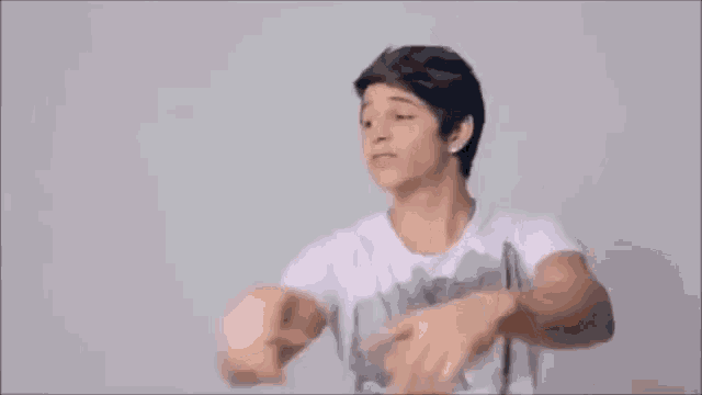 a young man in a white shirt is pointing at the camera with his fingers .