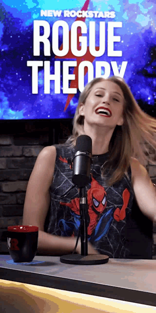 a woman laughs in front of a microphone in front of a sign that says new rockstars rogue theory