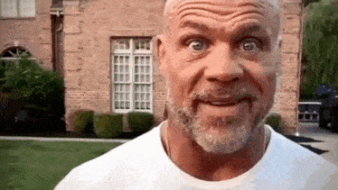 a man with a beard and mustache is making a funny face in front of a brick house .