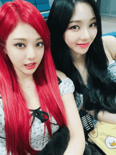 two girls with red hair and black hair pose for a photo
