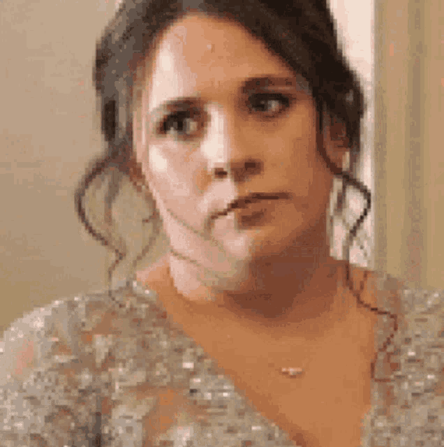 a woman in a dress and necklace is looking at the camera .