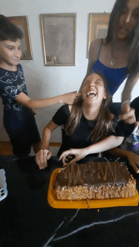 a girl is laughing while a boy holds her ear and another girl holds her head