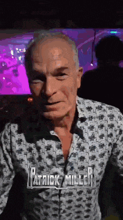 a man with the name patrick miller on his shirt is standing in a dark room .
