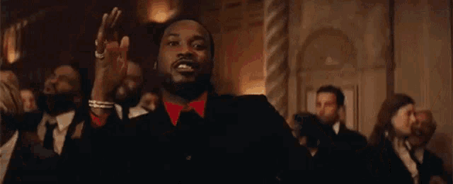 a man in a suit and red shirt is standing in front of a group of men in suits .