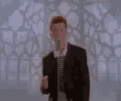 a man in a suit and striped shirt is singing into a microphone .
