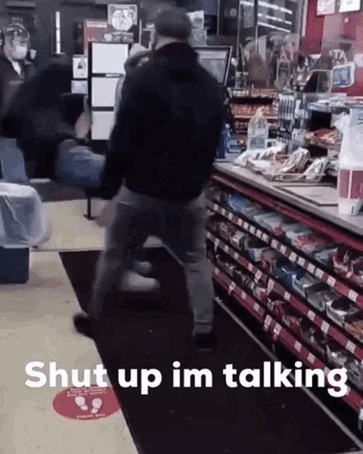 a man is standing in a store with the words shut up im talking behind him