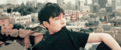 a young man in a black shirt is standing in front of a city .