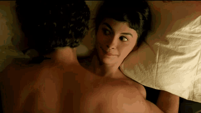 a woman laying on a man 's back looking at him