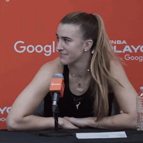 a woman sitting at a table with a microphone in front of a sign that says google