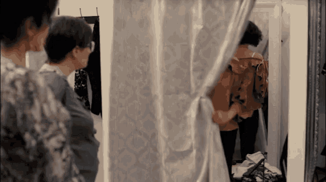 a woman is standing in a dressing room looking at herself in a mirror