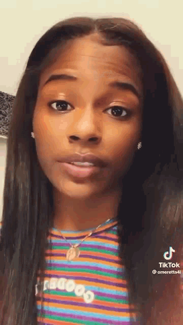 a close up of a woman 's face with a striped shirt and necklace .