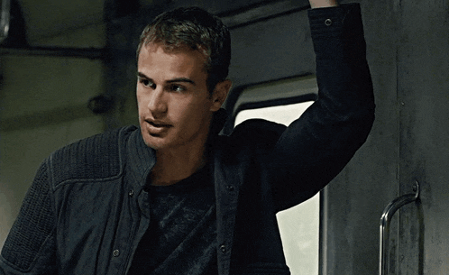 a man in a black jacket is holding up his arm