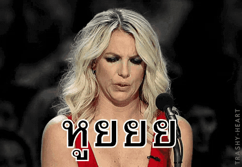 a woman in a red dress stands in front of a microphone with the word trashy on the bottom left