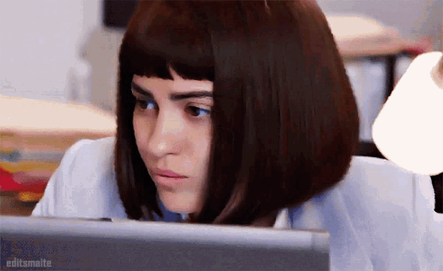 a close up of a woman looking at a laptop with editsmaite written below her