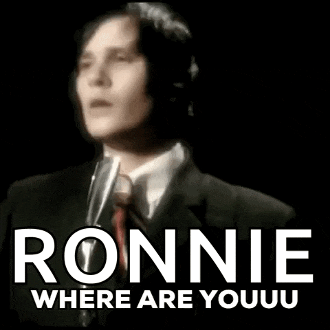 a man in a suit and tie is singing into a microphone with the words ronnie where are youuu below him .