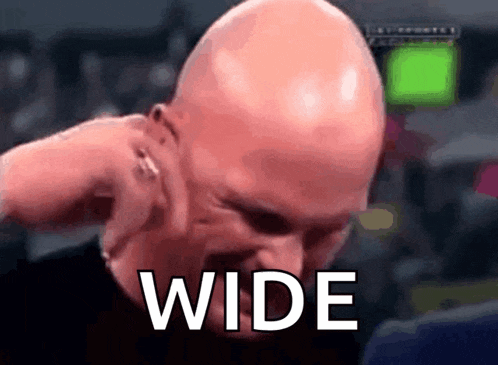 a bald man is covering his ears with his hand and the word wide is on the screen behind him .