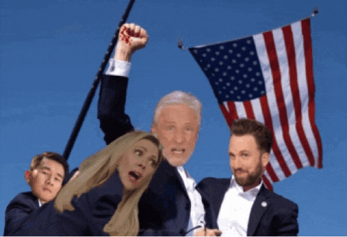 a man in a suit holds up his fist while a woman looks on