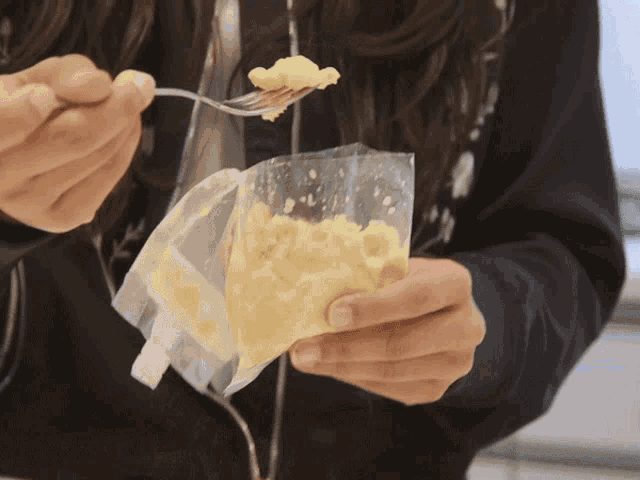 a person is holding a bag of food and a fork