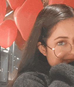 a close up of a woman wearing glasses and a grey sweater