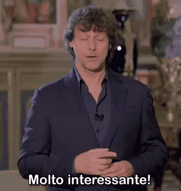 a man in a suit is standing in front of a wall and saying molto interessante .