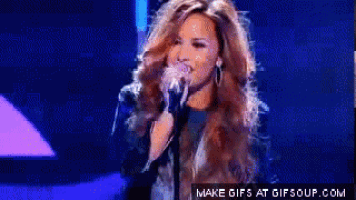 a woman singing into a microphone with the words make gifs at gifsoup.com on the bottom right