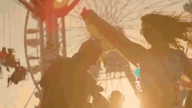a man and a woman are dancing at a carnival in front of a ferris wheel .