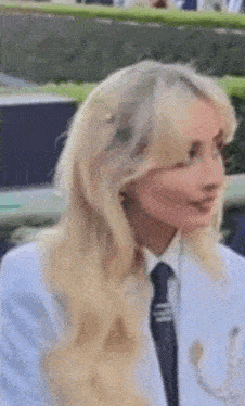 a close up of a woman wearing a white jacket and tie .