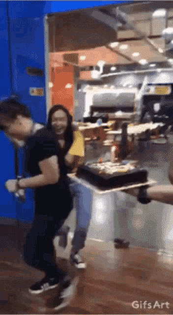 a man carrying a cake in a restaurant with a gifs art watermark on the bottom