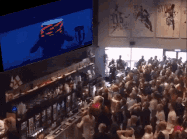 a large crowd of people are gathered in a bar watching a game