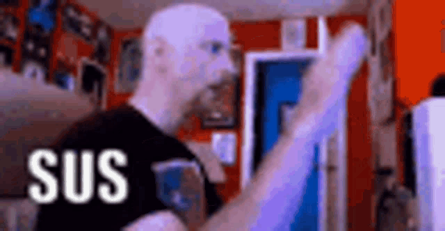 a man is standing in a room with his fist in the air and the word sus is visible .