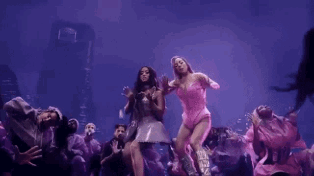 two women are dancing on stage in front of a crowd of people .