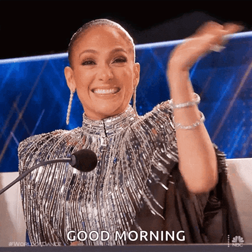 a woman in a silver dress is sitting in front of a microphone and says good morning