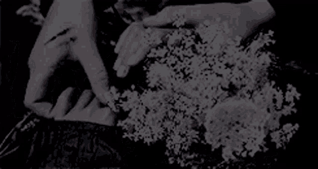 a close up of a person 's hands holding a bouquet of white flowers