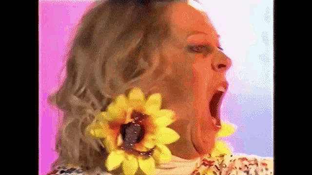 a woman wearing a pair of yellow sunflower earrings is making a funny face .
