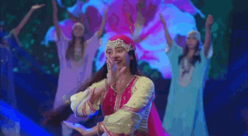 a woman in a traditional dress is dancing on a stage with other dancers .