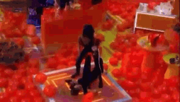 a woman is doing a handstand on a purple mat in a room filled with red balloons .