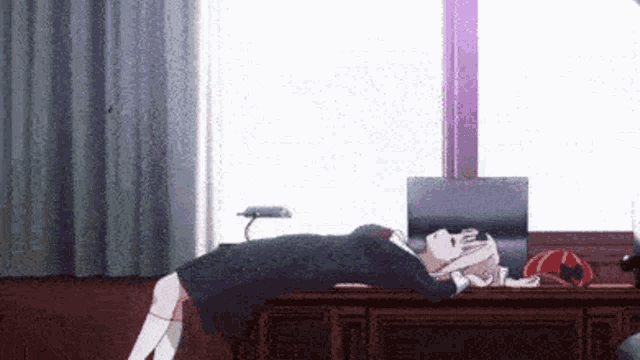 a girl is laying on a desk next to a window .