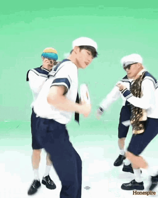 a group of young men are dancing in front of a green background and the words honespirre are on the bottom