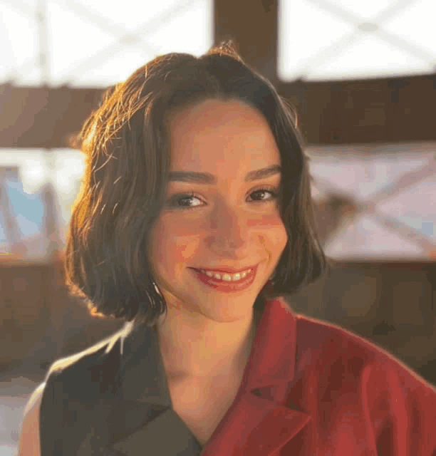 a woman wearing a red jacket and a black vest smiles for the camera