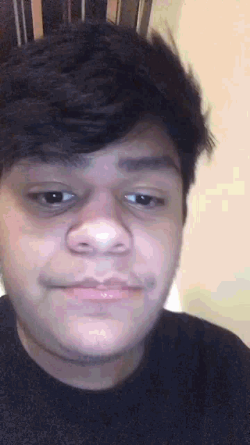 a young man with a beard is making a funny face while wearing a black sweater .