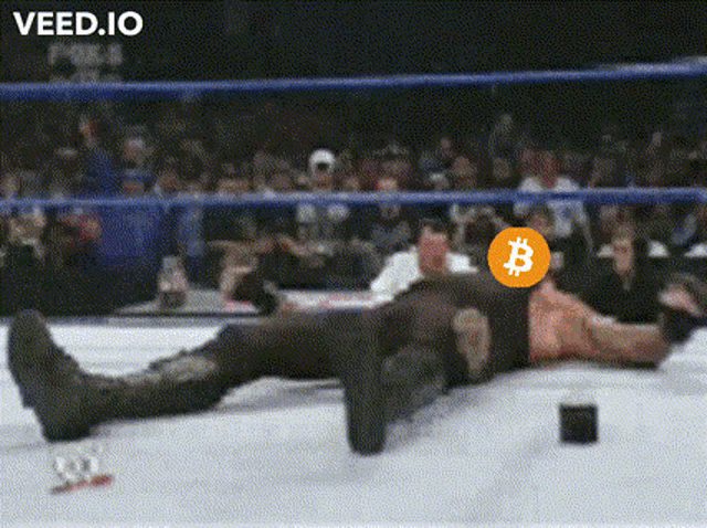 a wrestler is laying on the ground with a coin with the letters b on it