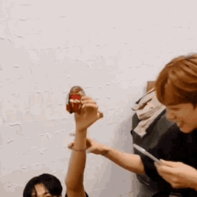 a man is holding a can of soda in his hand while another man holds a knife in his hand .