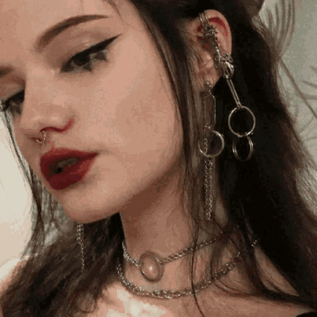 a close up of a woman 's face wearing earrings and a necklace