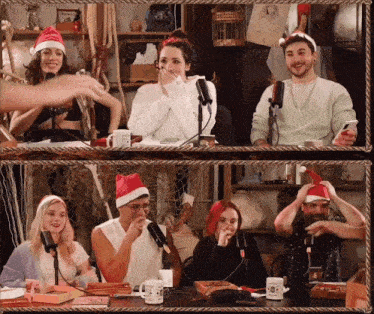 a group of people wearing santa hats are sitting around a table with microphones