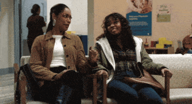 two women sit on a couch in front of a sign that says " help your physician immediately "