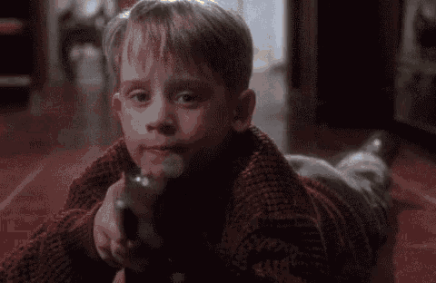 a boy in a red sweater is laying on the floor holding a remote control